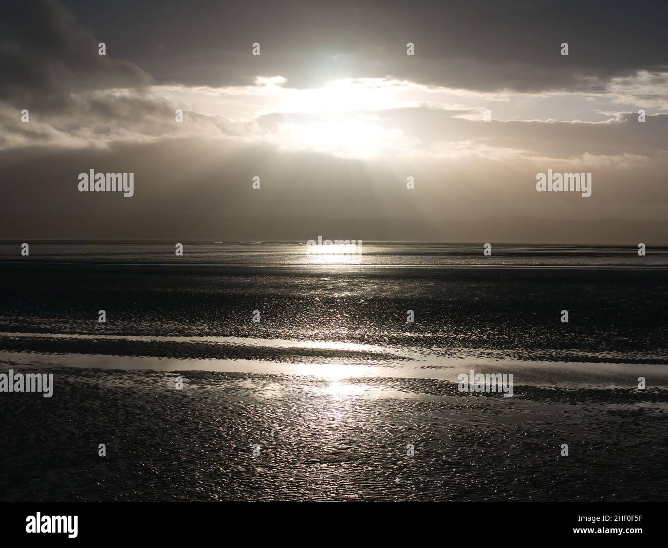 Le soleil se brise à travers les nuages au-dessus des vasières de l'estuaire de la Dee à marée basse à West Kirby sur Wirral dans le nord-ouest de l'Angleterre.La côte du Nord-Ouest Banque D'Images