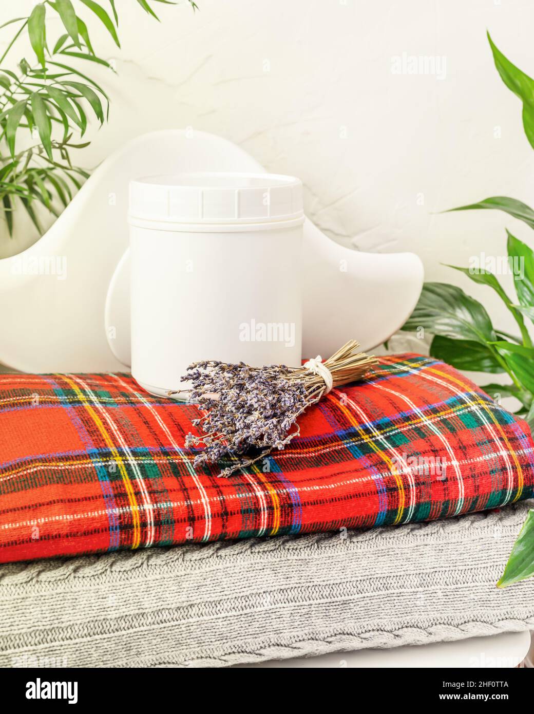Une bouteille de détergent pour laver les objets de laine sur une pile de couvertures tricotées avec un bouquet de lavande.Le concept de ménage, de nettoyage et de h Banque D'Images