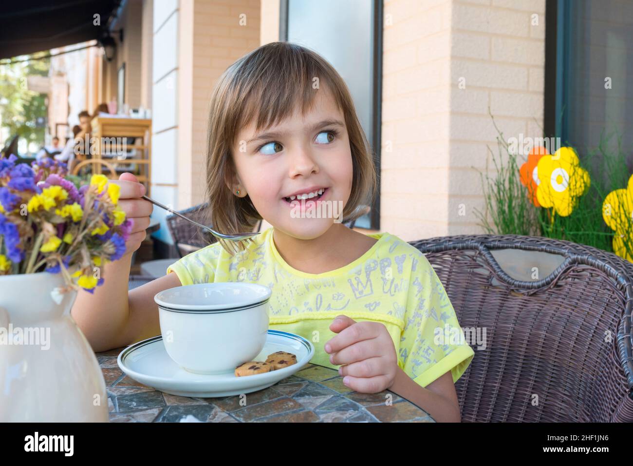 Petite fille a le petit déjeuner avec une tasse de thé et des biscuits au chocolat Banque D'Images