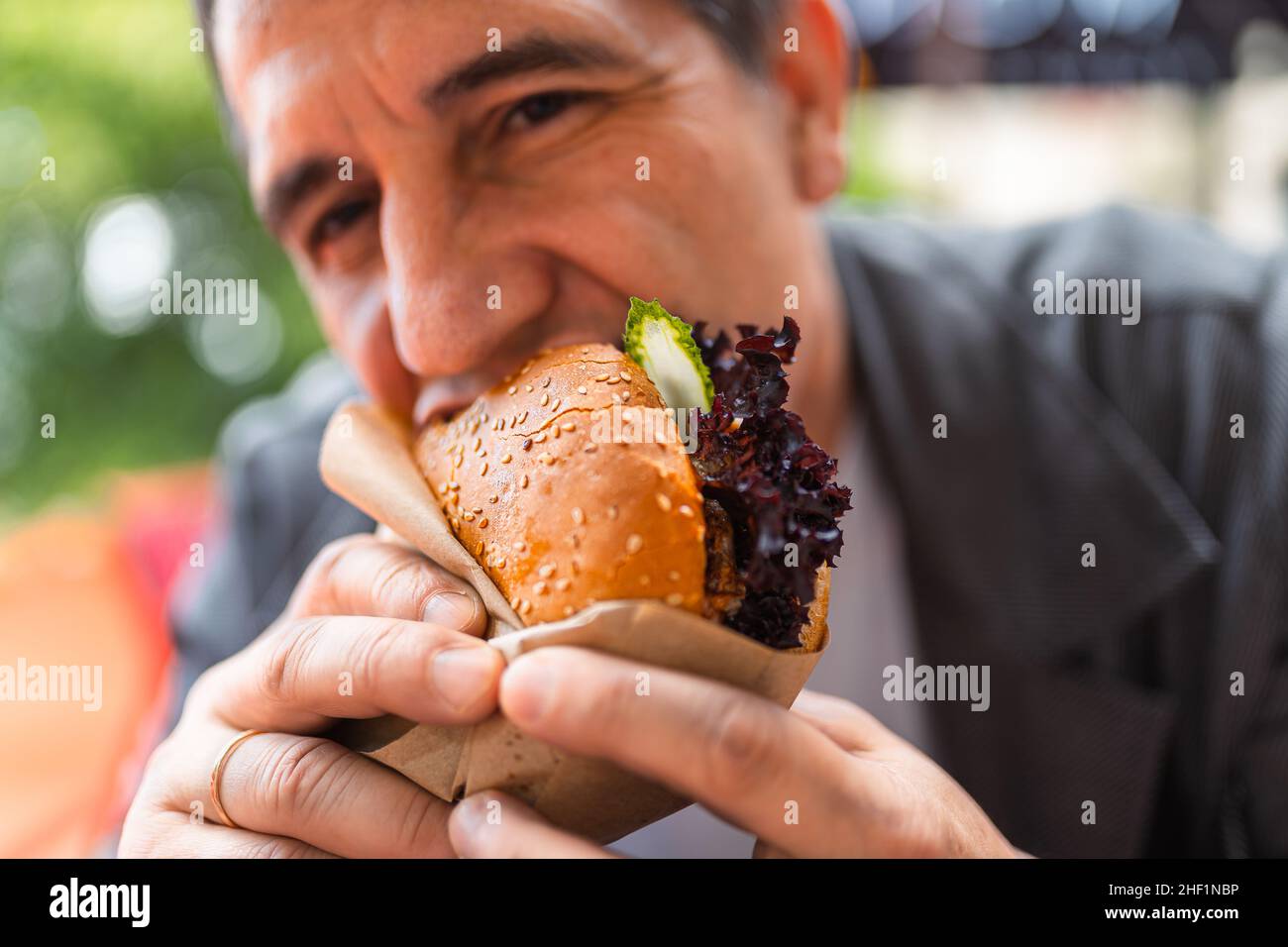 un homme avarié et gourmand mange un hamburger dans un restaurant de restauration rapide et apprécie un délicieux repas Banque D'Images