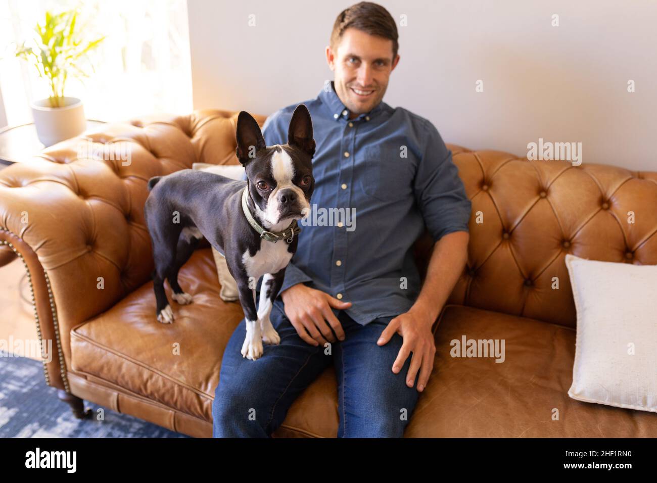 Portrait d'un homme et d'un chien caucasiens assis sur le canapé à la maison Banque D'Images