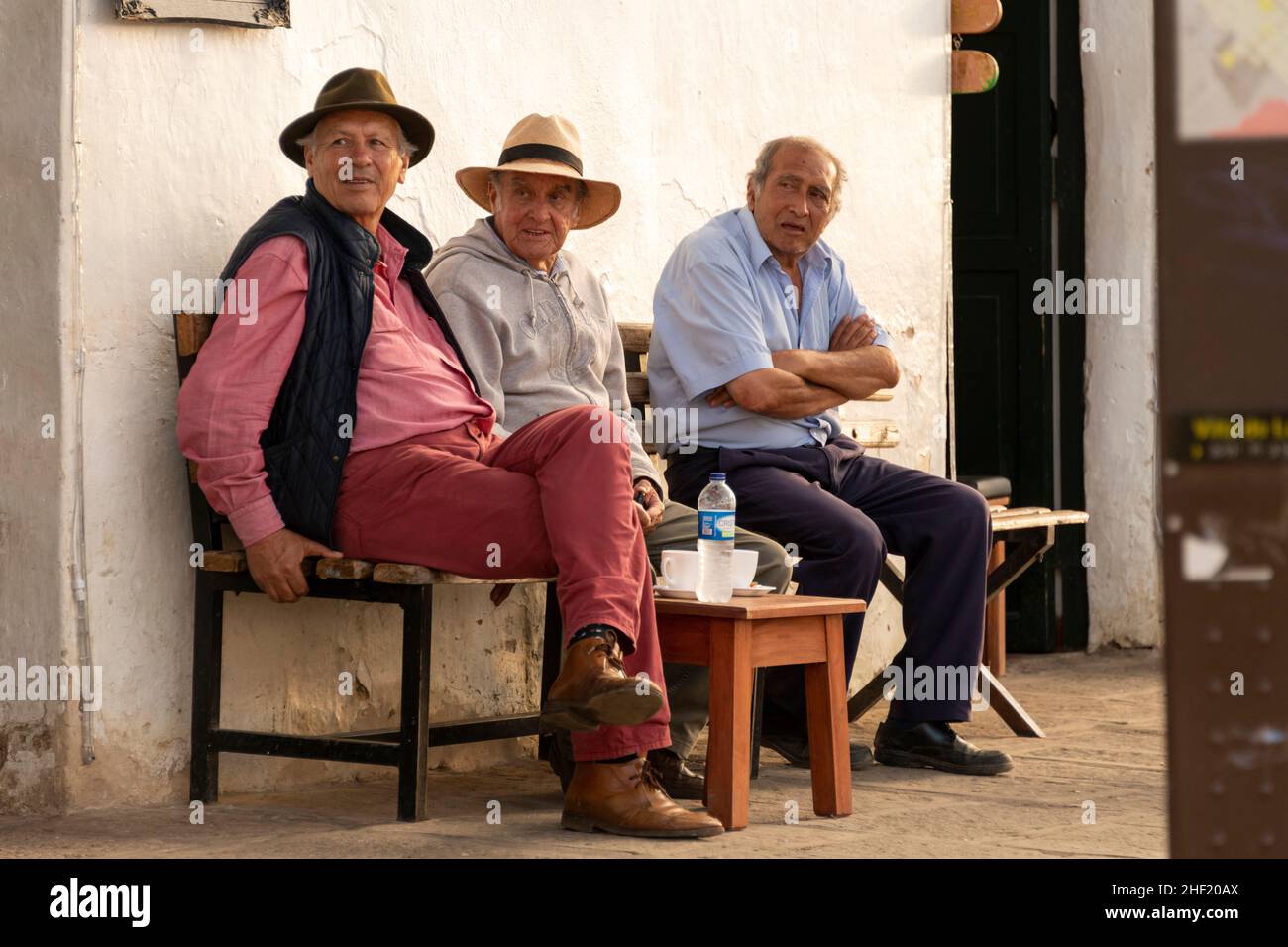 Trois hommes se détendent sur la Plaza coloniale Mayor de Villa de Leyva, Boyacá, Colombie.Regarder le monde passer. Banque D'Images