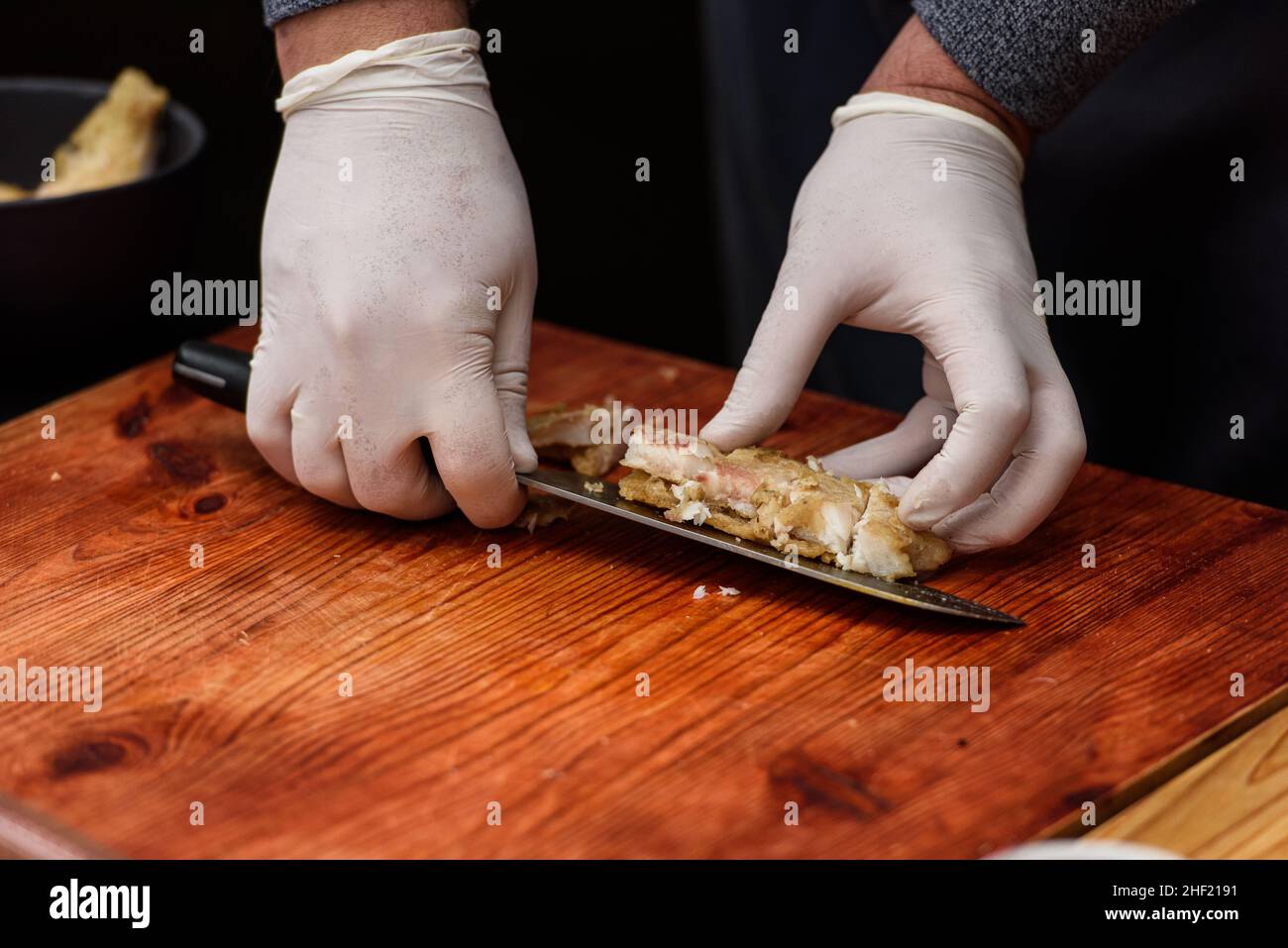 L'homme coupe du poisson frit, le processus de cuisson de la soupe Suquet de Peix avec des pommes de terre Banque D'Images