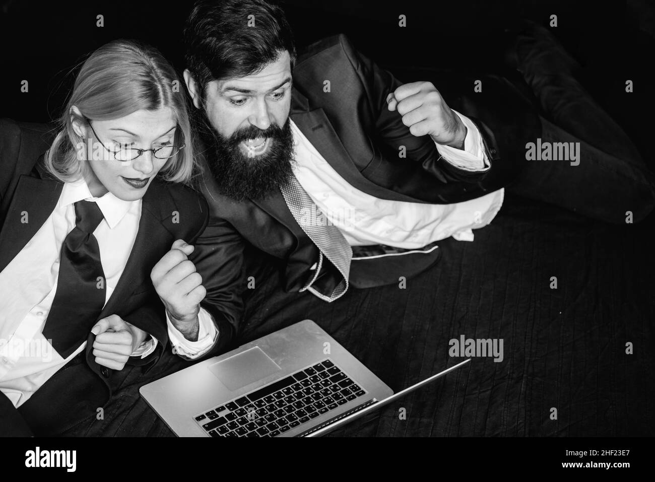 Portrait de deux professionnels enthousiastes regardant un écran d'ordinateur portable. Pirates utilisant des ordinateurs portables. Pirates informatiques dans l'obscurité. Banque D'Images