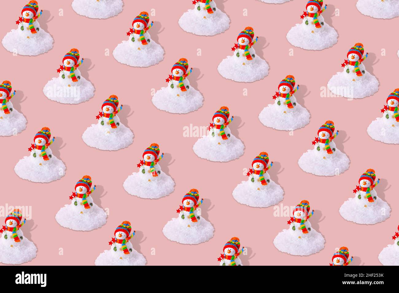 Motif hivernal créatif avec bonhomme de neige et neige sur fond rose pastel. Banque D'Images