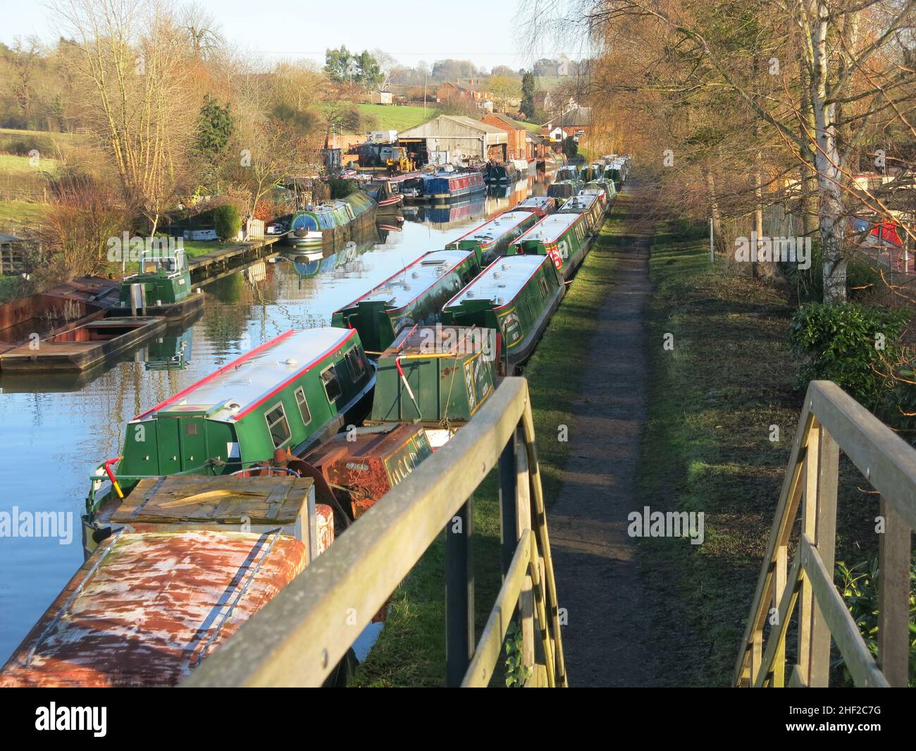 Vue vers l'est le long du canal de Grand Union à Braunston, avec des bateaux étroits amarrés le long des pistes de remorquage ; une journée d'hiver ensoleillée en janvier 2022. Banque D'Images