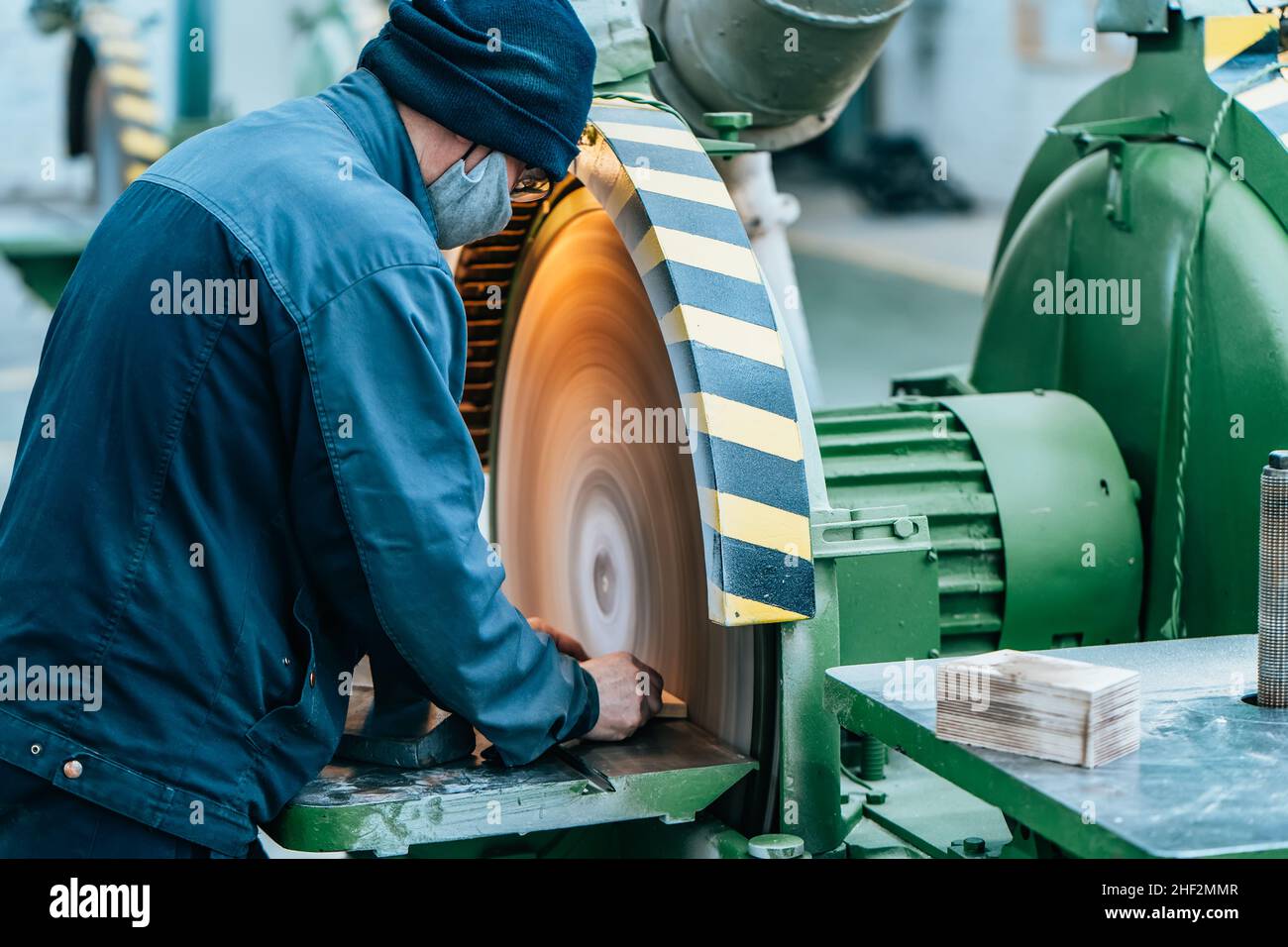 Travailleur en uniforme dans une grande rectifieuse industrielle de l'usine de bois pour la production de meubles. Banque D'Images