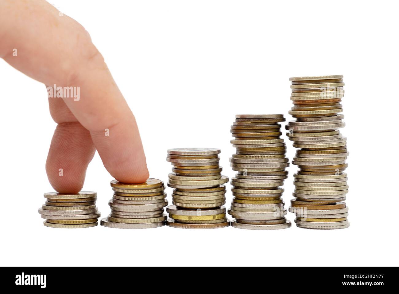 Les doigts font des pas sur des piles de pièces sur fond blanc.Concept de croissance monétaire et de réalisation d'objectifs financiers.Affaires et finances. Banque D'Images