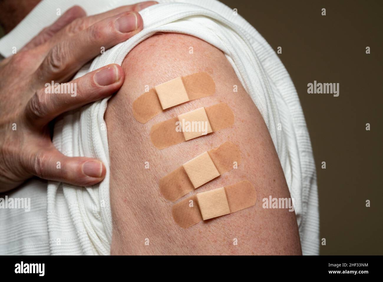 Manchon d'homme caucasien âgé pour montrer le quatrième vaccin de rappel contre le coronavirus dans l'épaule.Concept avec quatre bandages séparés pour les prises de vue Banque D'Images