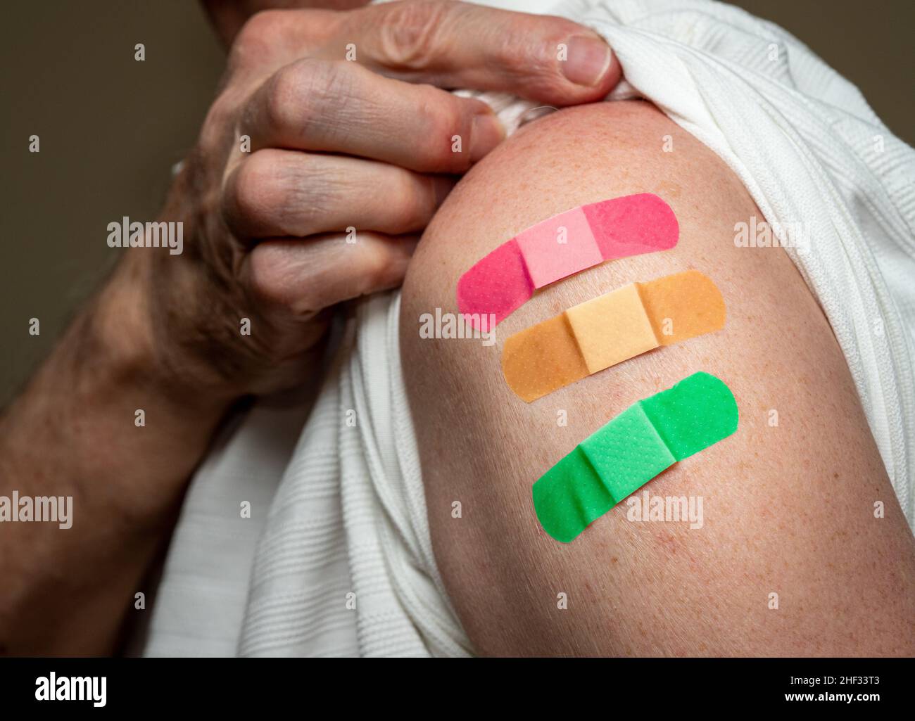 Manchon d'homme caucasien âgé pour montrer le troisième vaccin de rappel contre le coronavirus dans l'épaule.Concept avec trois bandages séparés pour les prises de vue Banque D'Images