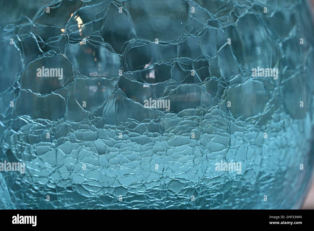 Gros plan sur une sphère en verre bleu aqua avec motif craquelé. Banque D'Images