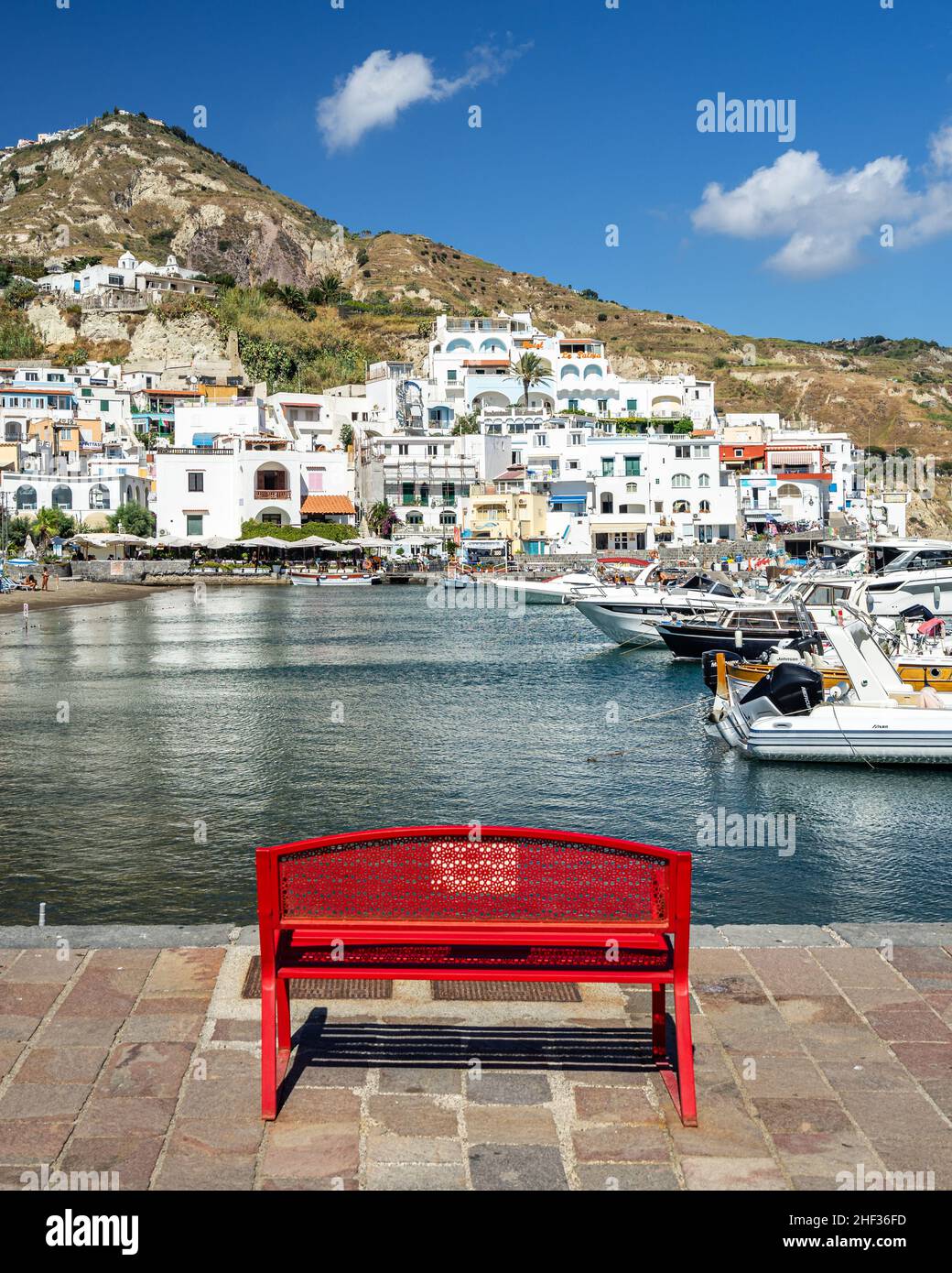 Un banc rouge coloré face au port de Sant’Angelo d’Ischia, en Italie Banque D'Images