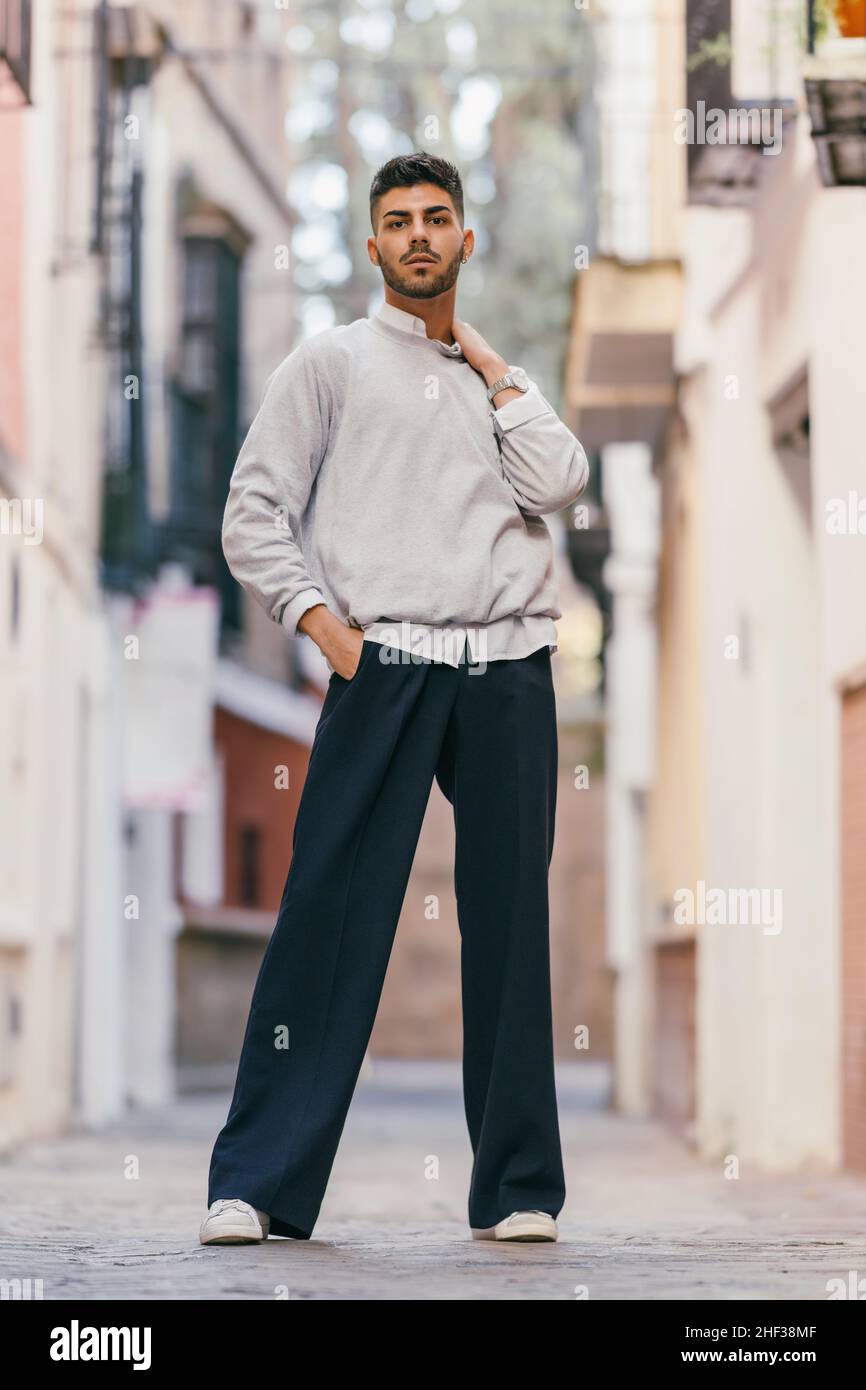 Jeune homme debout tout en regardant la caméra avec une expression fière à l'extérieur Banque D'Images