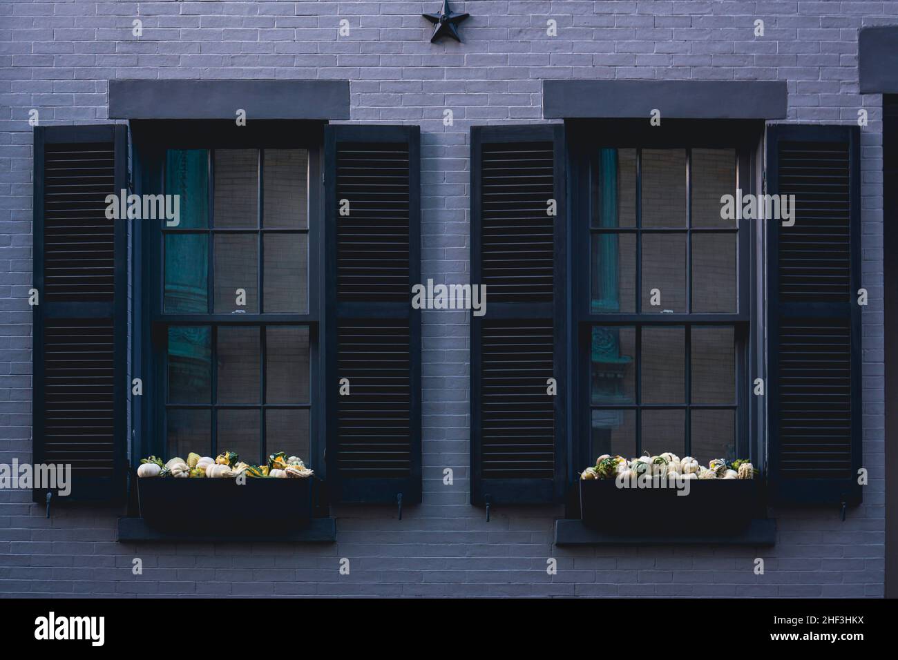 Fenêtres traditionnelles avec volets en bois noir sur un mur en brique grise d'un immeuble d'appartements Banque D'Images
