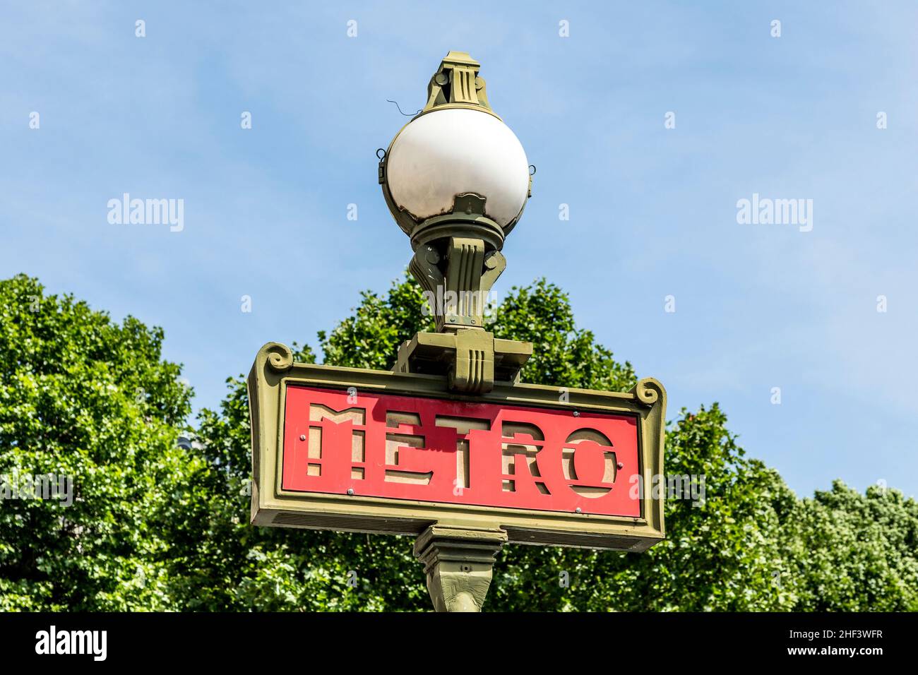 Métro parisien signe avec un lampadaire contre le ciel bleu Banque D'Images