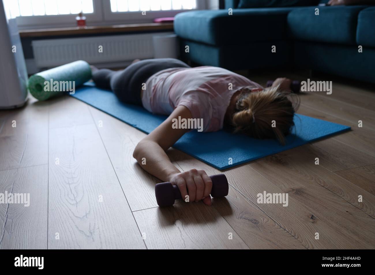 Une femme de sport fatiguée avec des haltères se trouve sur le sol Banque D'Images