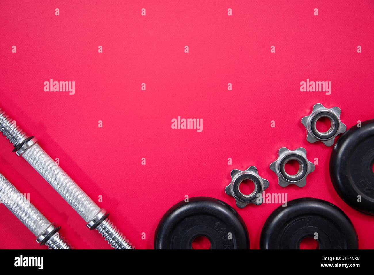 Fitness ou musculation.Équipement sportif sur fond rouge : haltères, cloches, vue de dessus avec beaucoup d'espace pour copier. Banque D'Images