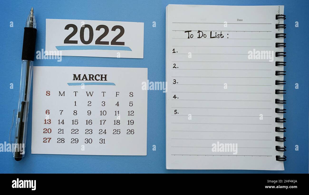 Texte de liste des tâches écrit à la main sur le bloc-notes pour le mois de mars avec un stylo et un fond bleu.concept de la nouvelle année 2022. Banque D'Images
