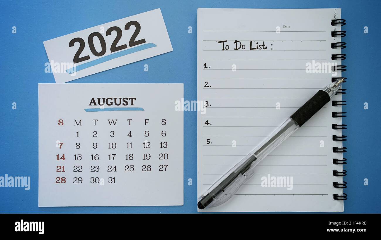 Texte de liste des tâches écrit à la main sur le livre de notes pour le mois d'août avec un stylo et un arrière-plan bleu.concept de la nouvelle année 2022. Banque D'Images