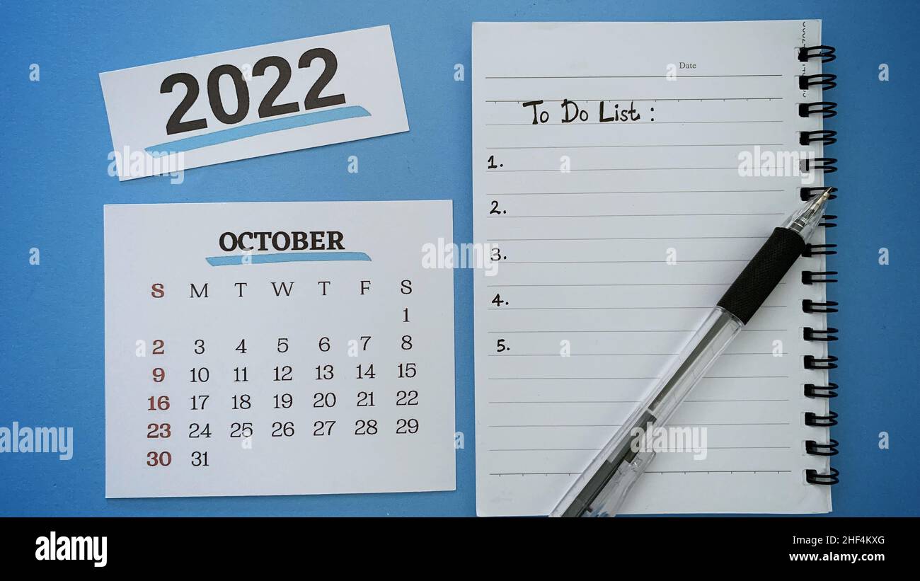 Liste des tâches écrite sur le bloc-notes du mois d'octobre avec un stylo et un fond bleu.concept de la nouvelle année 2022. Banque D'Images