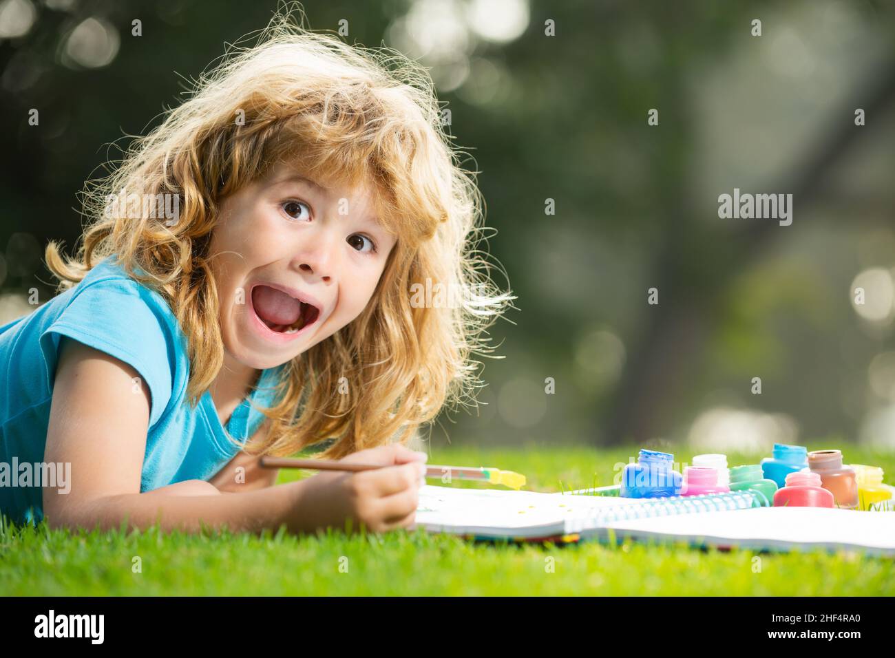 Peinture excitée pour enfants dans la nature printanière.Portrait d'un joyeux gamin souriant qui apprécie l'art et le dessin d'artisanat dans l'arrière-cour ou le parc de printemps.Dessin enfant Banque D'Images
