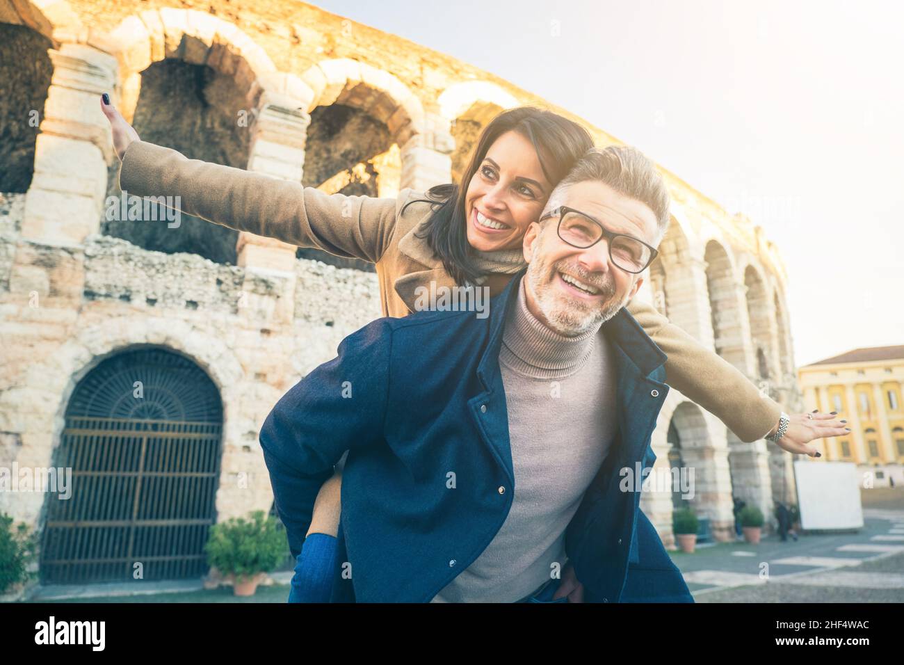Heureux couple senior dans l'amour s'amuser en face du célèbre monument de l'Italie.Vue en contre-angle d'une femme gaie qui s'étire les bras tout en étant assise Banque D'Images