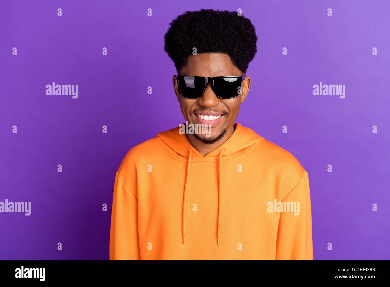 Photo de l'hipster brunet jeune gars porter des lunettes orange sportswear isolé sur fond violet couleur Banque D'Images