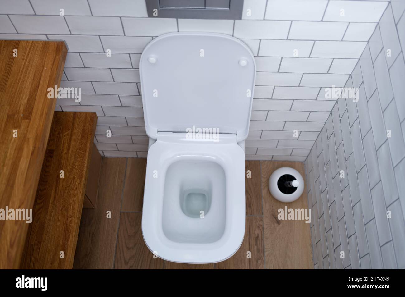 Nettoyer la cuvette de toilette dans un wc à carreaux blancs Banque D'Images