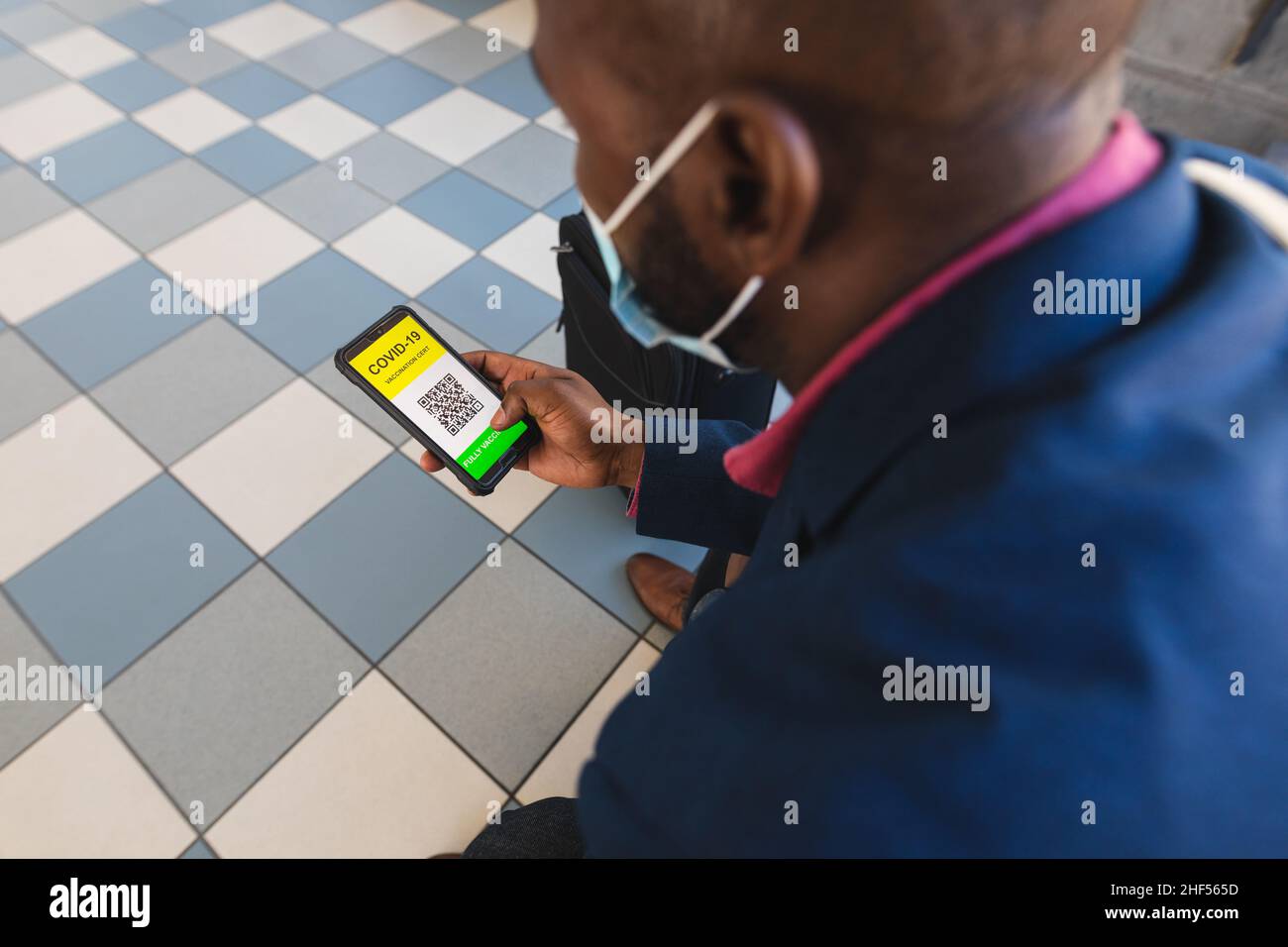 Homme d'affaires avec un certificat de vaccination Covid-19 sur son écran de smartphone lors de ses déplacements au bureau Banque D'Images