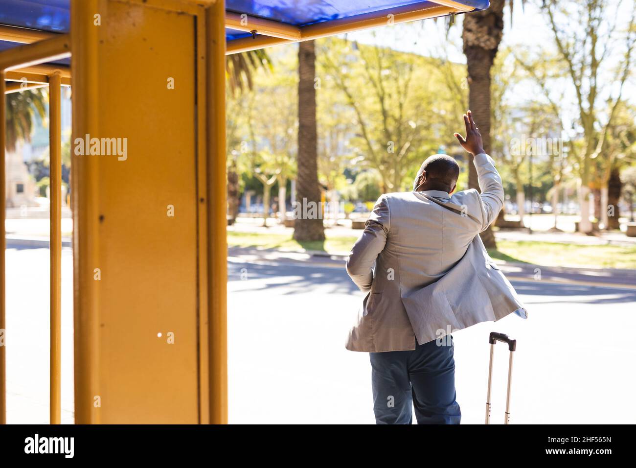 Vue arrière d'un homme d'affaires avec une valise en train de transporter un taxi dans la rue sur le bureau Banque D'Images