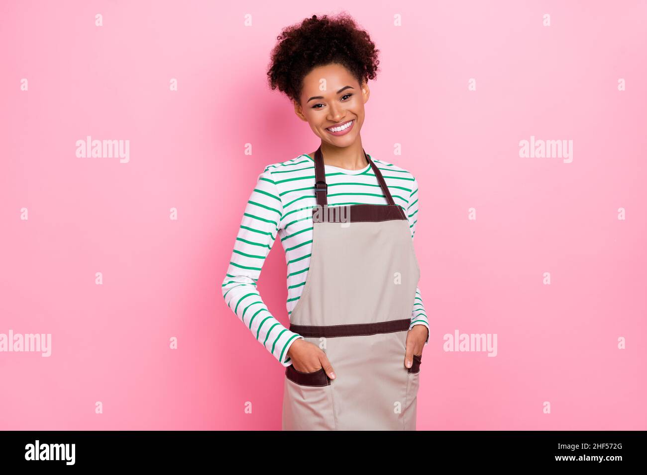 Photo de rêve gai joli joli Barista filles mains poches porter tablier rayé chemise isolée couleur rose fond Banque D'Images