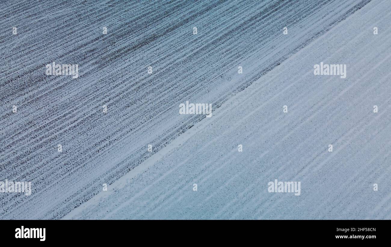 Vol sur un terrain enneigé.Des traces de labour agricole sont visibles sous la neige.Photographie aérienne. Banque D'Images