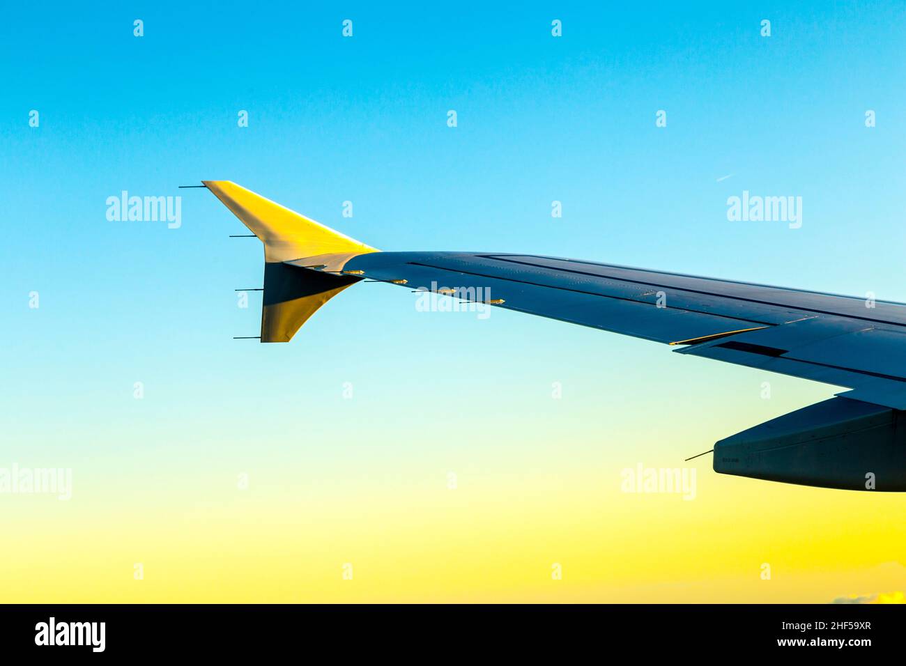 Aile de l'avion dans un ciel bleu au soleil de la fin de l'après-midi Banque D'Images