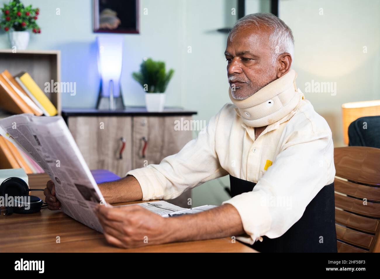 Sick senior avec le cou et la ceinture de soutien de ceinture de lecture de papier d'actualité à la maison - concept de la douleur senior de la peinture articulaire, le style de vie malsain et Banque D'Images