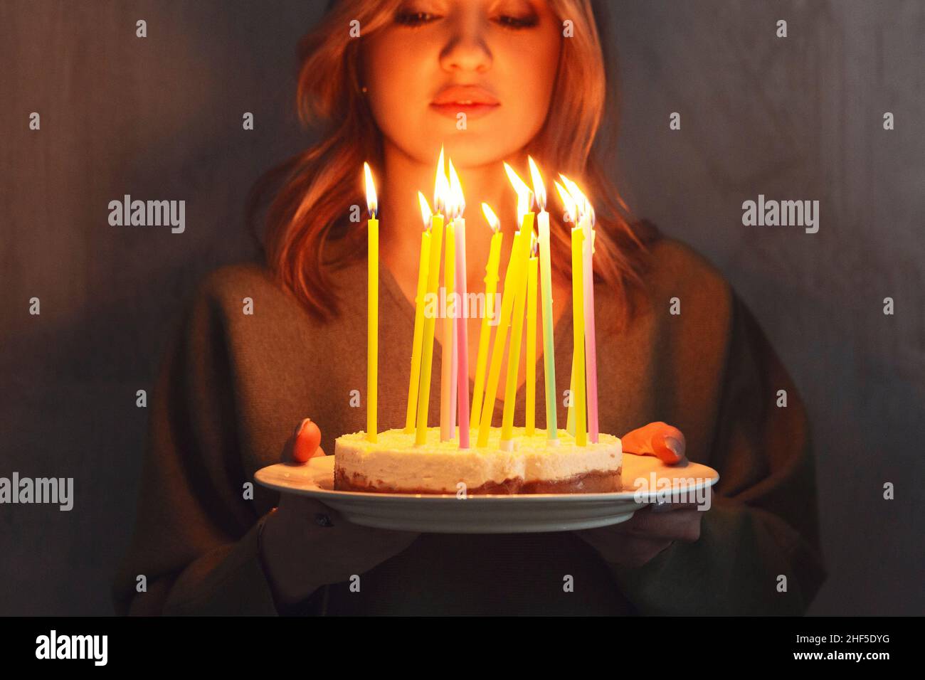 Jeune femme souriante tenant un gâteau d'anniversaire maison avec des bougies allumées à l'intérieur, vue latérale.Une femme apporte une tarte aux jours.Anniversaire traditio Banque D'Images