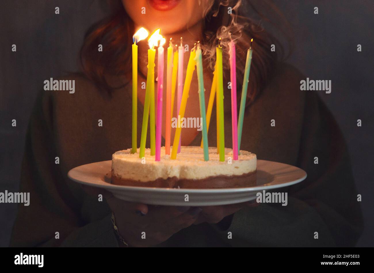 Jeune femme souriante tenant un gâteau d'anniversaire maison avec des bougies allumées à l'intérieur, vue latérale.Une femme apporte une tarte aux jours.Anniversaire traditio Banque D'Images