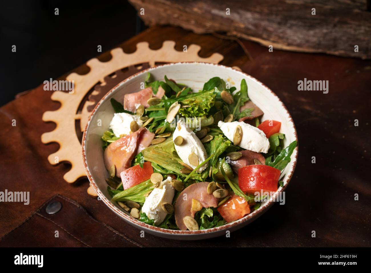 Salade de légumes frais avec légumes, poisson, fromage, œuf, graines de citrouille,Arugula en céramique blanche sur un tablier en cuir.Vue de dessus.Photo de haute qualité Banque D'Images