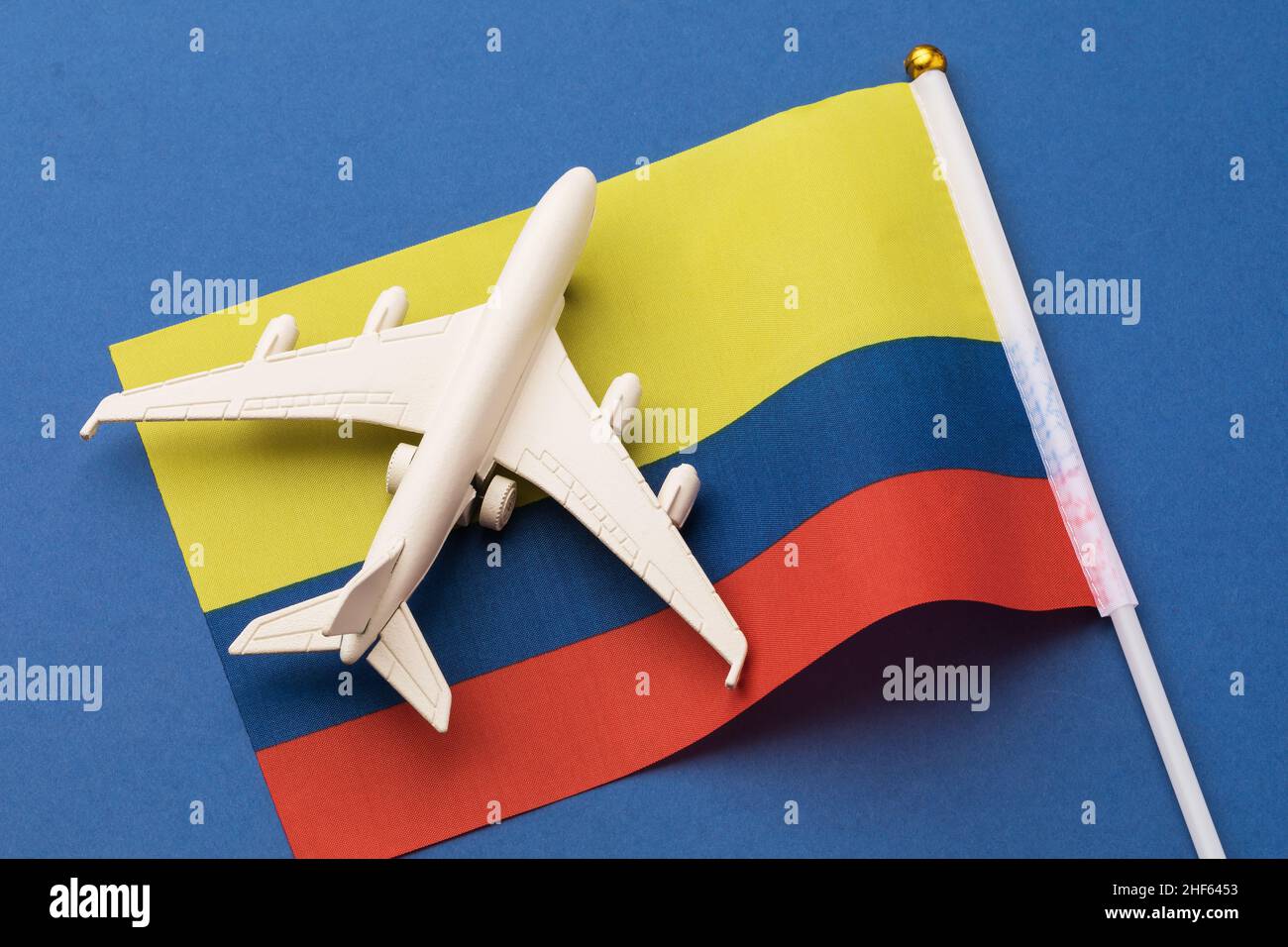Drapeau colombien et avion jouet sur fond bleu, concept de vol vers la Colombie, vue de dessus Banque D'Images