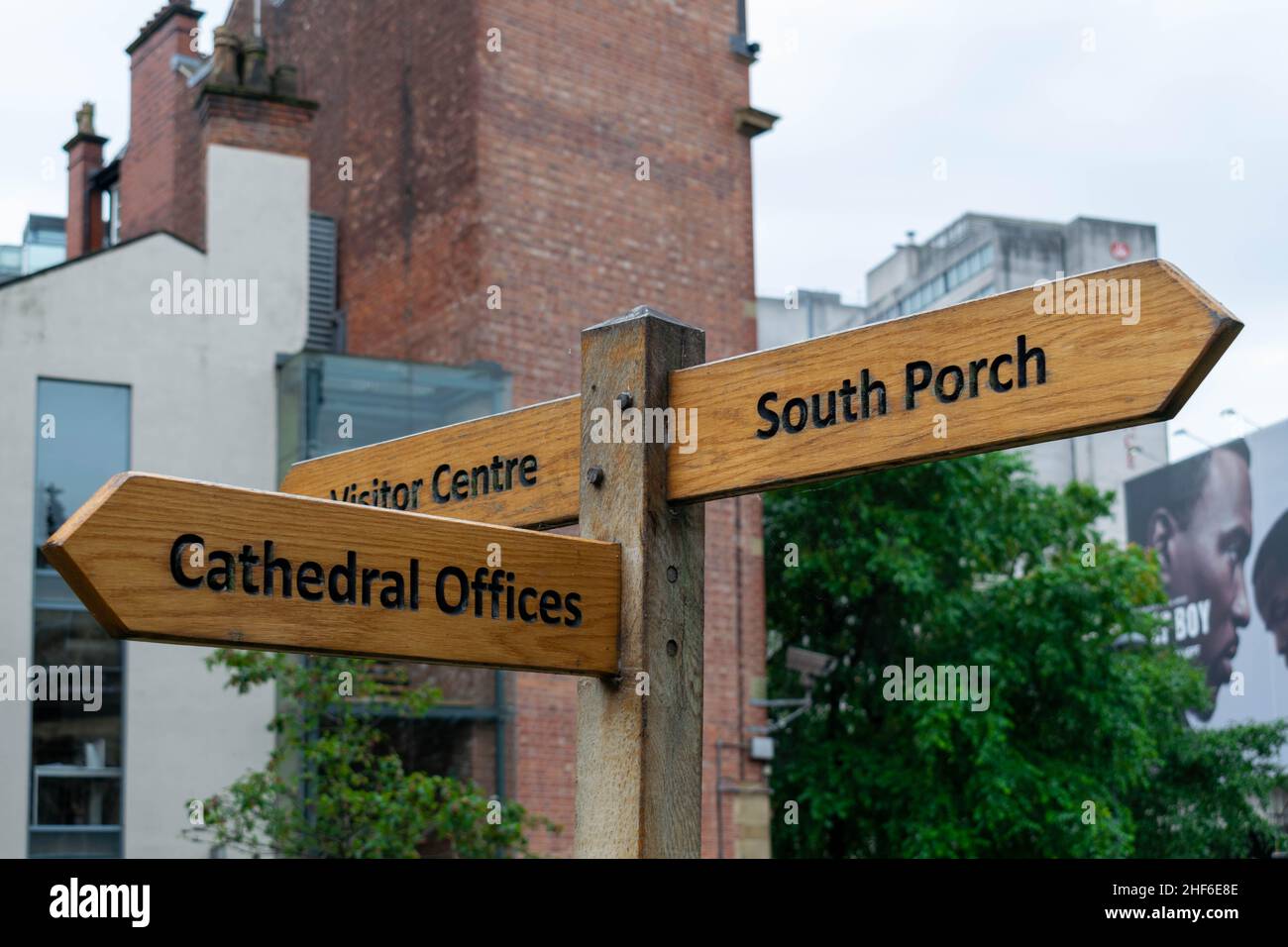 Panneau rustique en bois dirigeant les touristes et les visiteurs vers le centre des vainqueurs, les bureaux de la cathédrale et le porche sud dans le centre-ville de Manchester, Royaume-Uni, Angleterre Banque D'Images