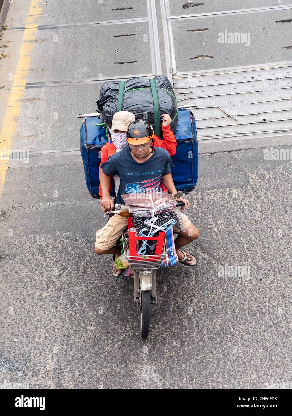 Au Vietnam, on peut souvent voir des motos transportant des charges lourdes.Voici un vieux vélo à Ho Chi Minh ville transportant deux personnes plus les produits et l'équipement Banque D'Images