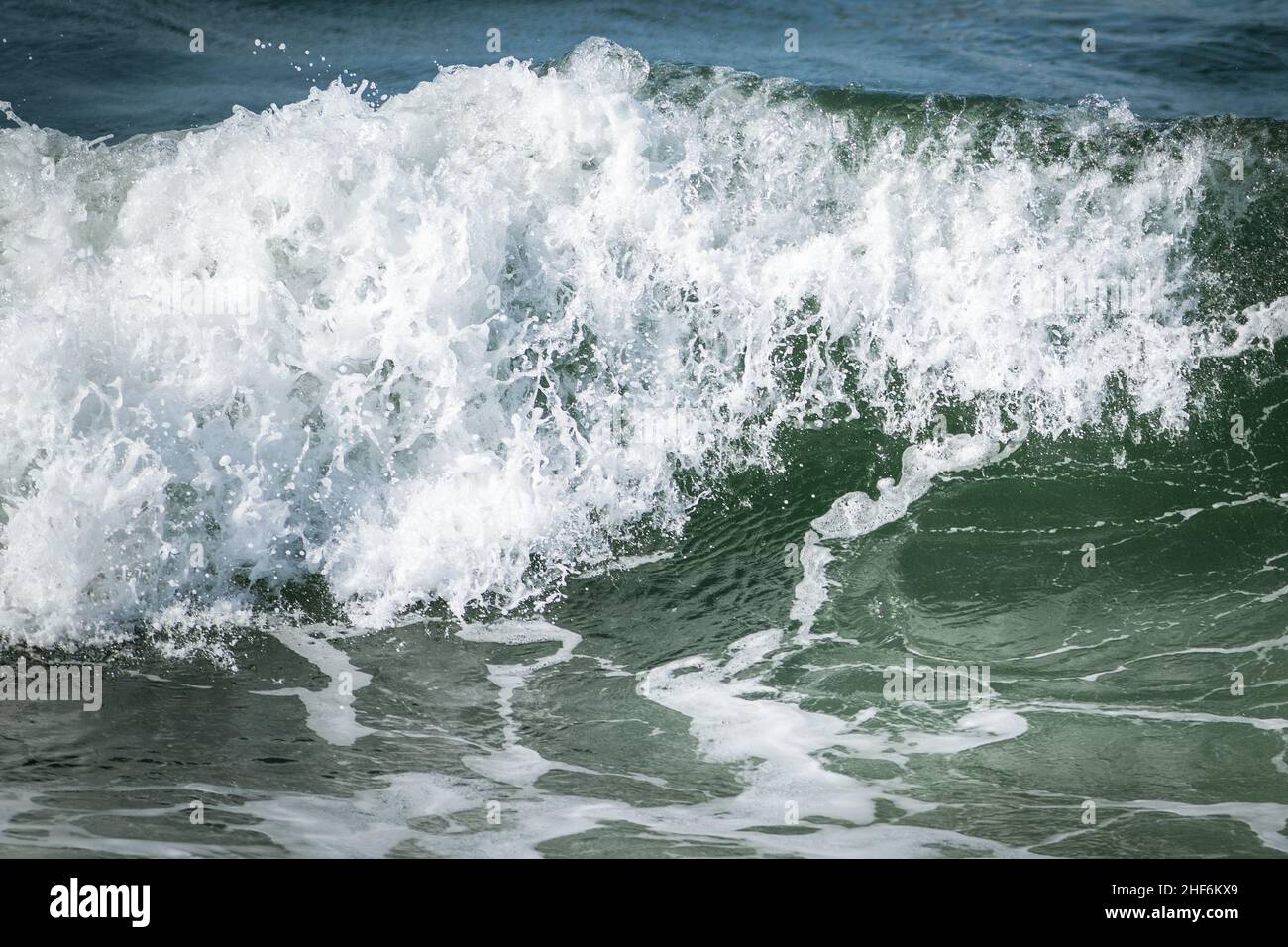 Une couleur vert turquoise en colère une boucle de rip massive d'une vague en roulant le long d'une plage.La brume blanche et la mousse de la vague sont mousseuse et moelleuse. Banque D'Images