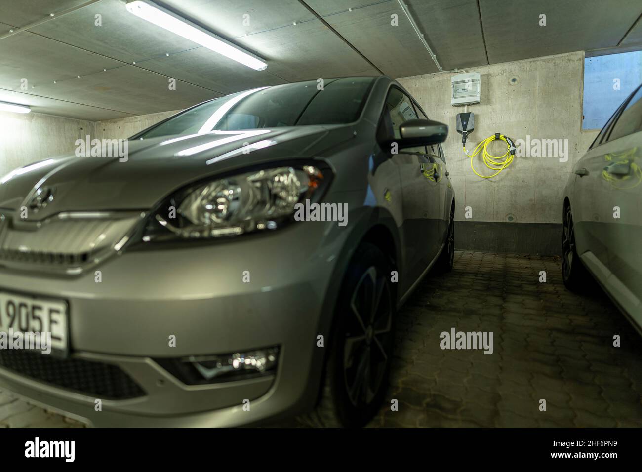 Voiture électrique avec son E typique à la plaque d'immatriculation et une station de charge Wallbox monté au mur en arrière-plan Banque D'Images