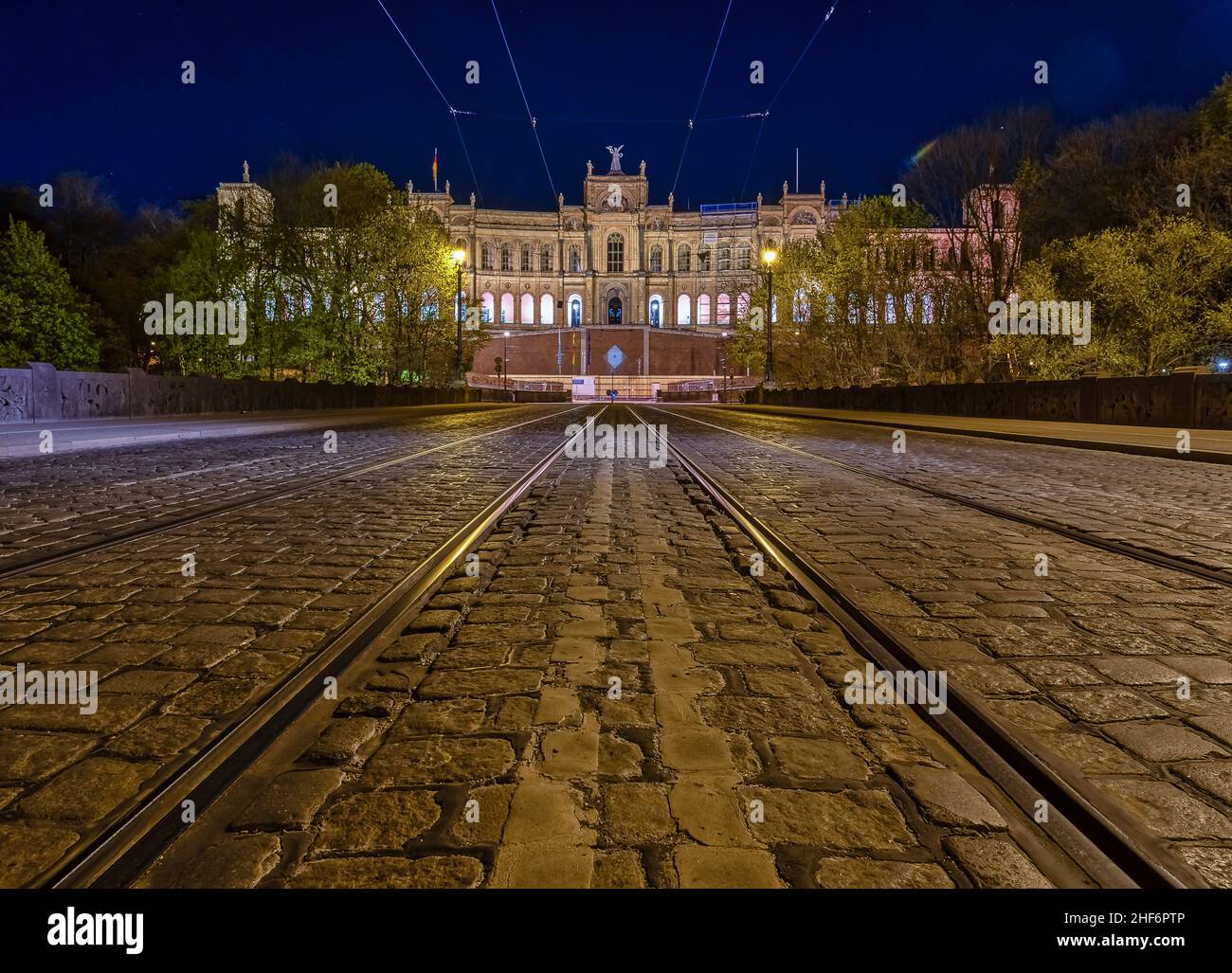 Vue symétrique à faible perspective sur une piste de tramway avec l'architecture populaire de Munich en arrière-plan la nuit Banque D'Images