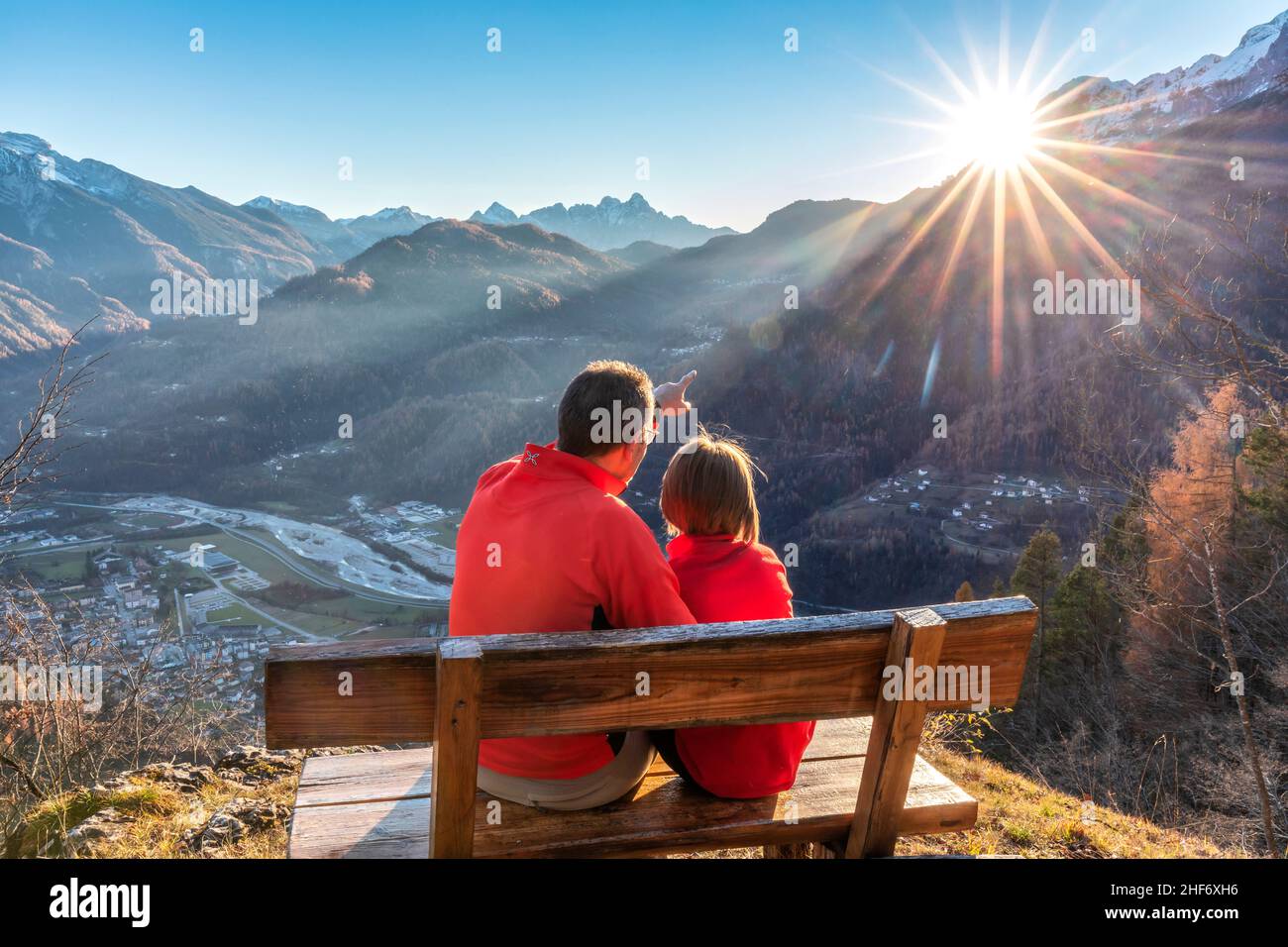 Deux personnes (père et fille) assis sur un banc en automne, regardant le coucher du soleil, Agordo, province de Belluno, Vénétie, Italie Banque D'Images