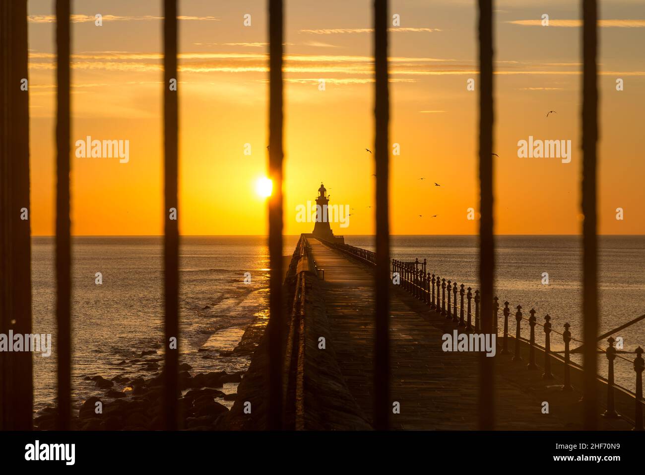 Tynemouth Pier et le phare à travers les chemins de fer en métal avec un beau lever de soleil vibrant Banque D'Images