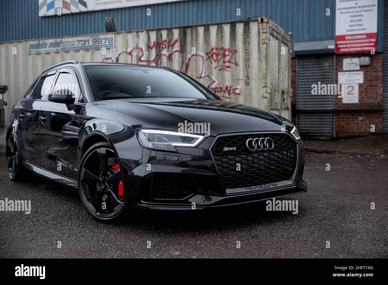 Un modèle Panther Black 2018 Audi RS3 à hayon avec jantes en alliage diamant et étriers de frein RS rouges sur Une zone industrielle sous la pluie Banque D'Images