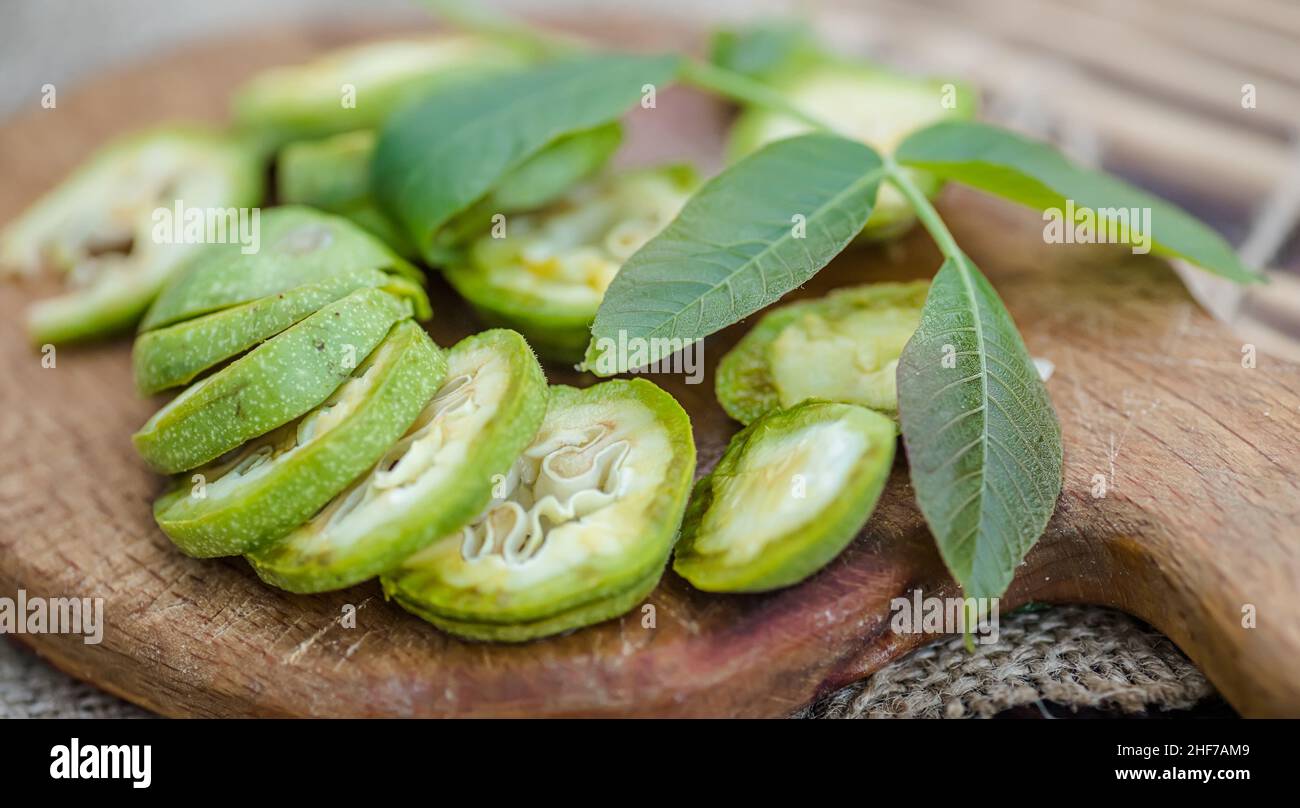 une alimentation saine.Les noix, coupées en tranches, sont dispersées sur une planche à découper.Ancienne table vintage et fruits de noyer entiers non mûrs. Banque D'Images