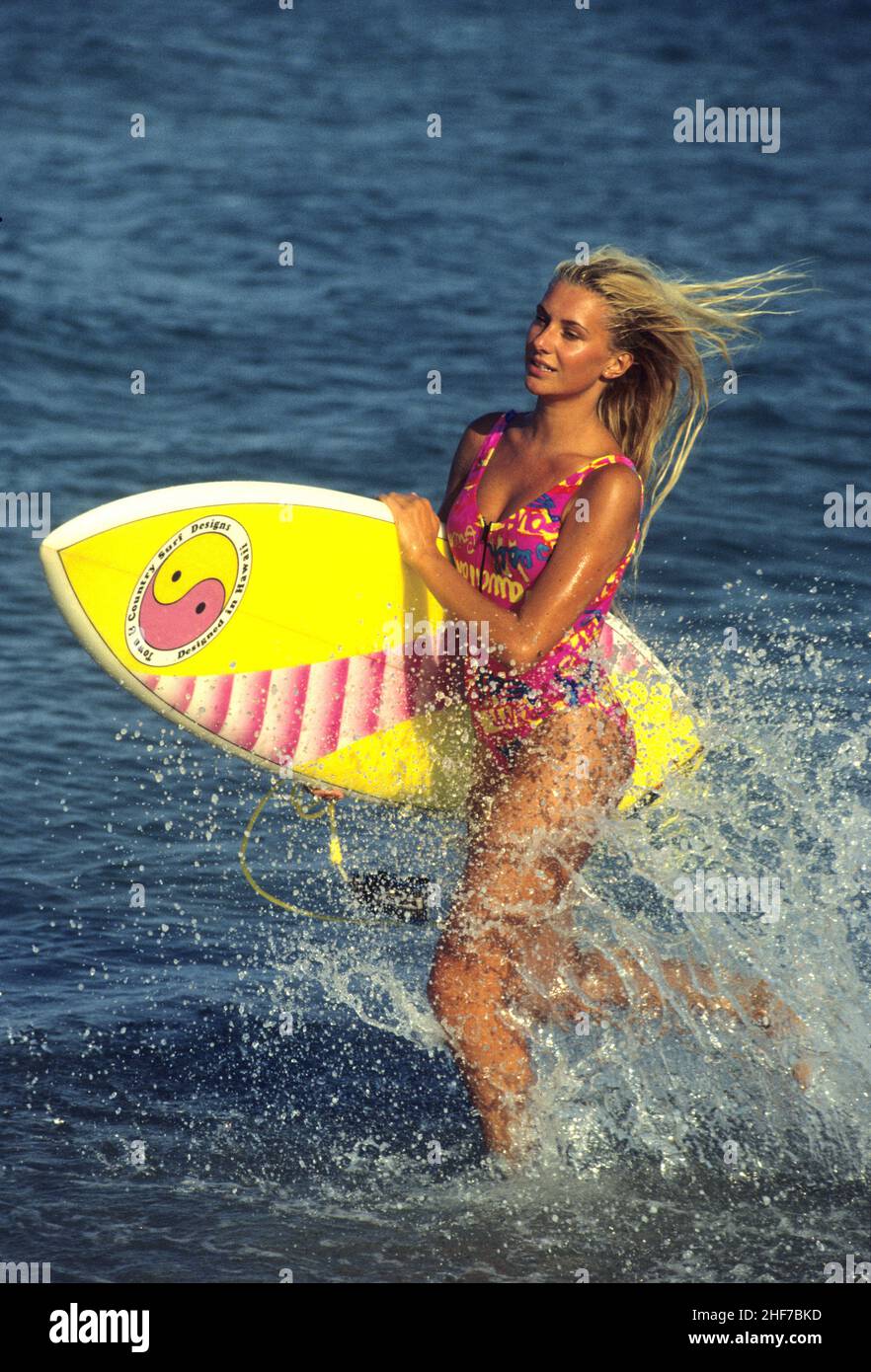 beauté cheveux blond attrayant silhouet sportif avec surf course sur la plage éclabousse un fond d'eau de mer Banque D'Images