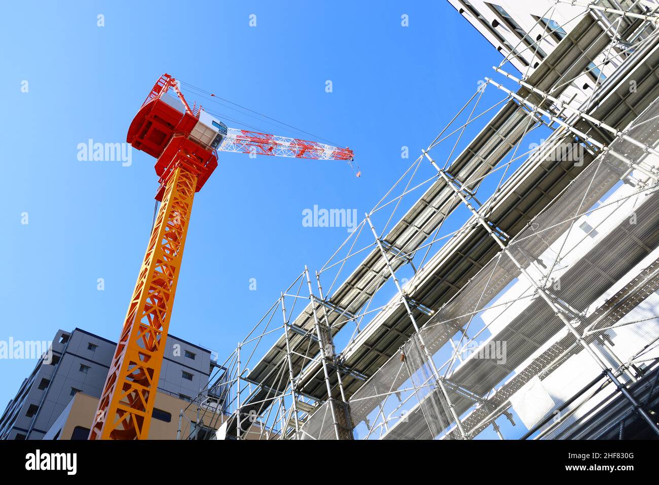 Ciel bleu clair et grues de construction colorées sur un chantier de construction Banque D'Images