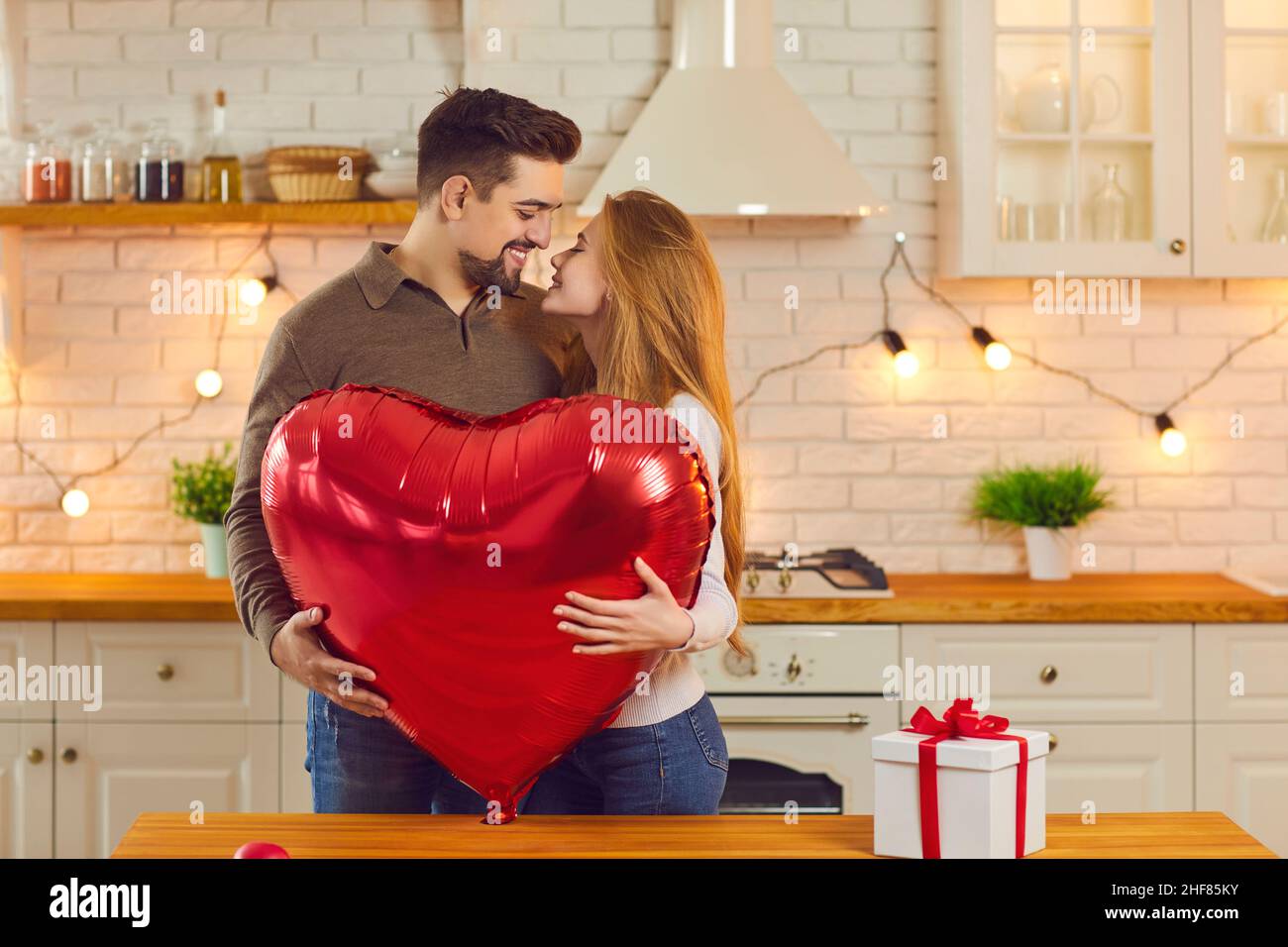 Joyeux jeune couple tenant une énorme montgolfière en forme de cœur et embrassant le jour de la Saint-Valentin Banque D'Images